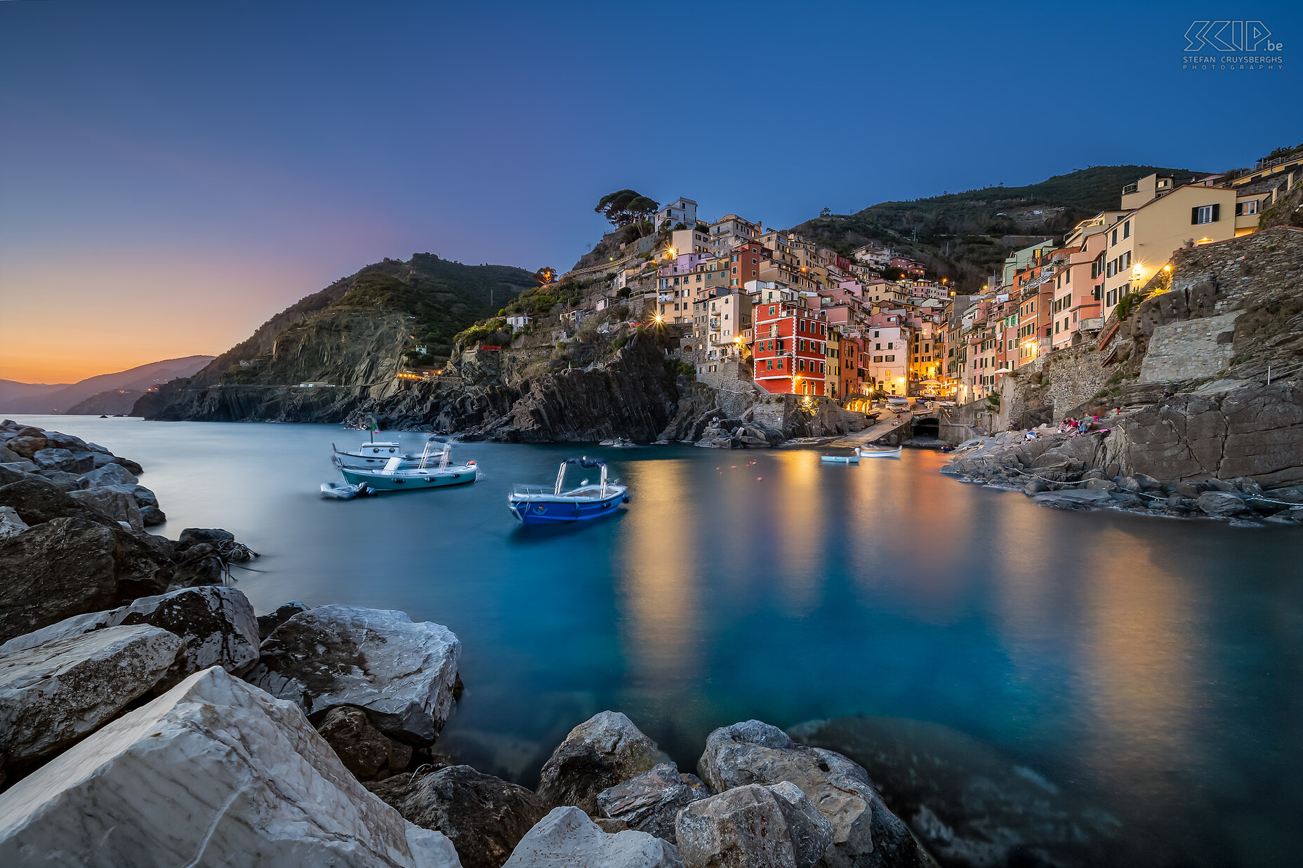 Riomaggiore - By night Riomaggiore is het meest zuidelijke dorp. Het ligt diep ingesneden tussen de heuvels, waarop terrassen zijn aangelegd voor de landbouw. De huizen hebben de typisch Ligurische kleuren (rood, roze, oker) en leunen tegen de helling aan. Riomaggiore telt zo'n 2.000 inwoners en is daarmee met Monterosso het grootste dorp. Het dorp ontstond al in de twaalfde eeuw. Stefan Cruysberghs